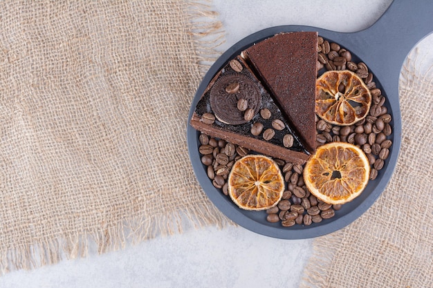 Zwei Scheiben Schokoladenkuchen mit Kaffeebohnen und Orangenscheiben. Foto in hoher Qualität