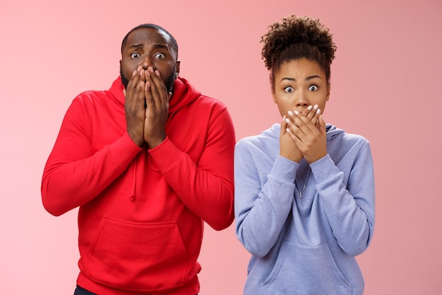 Zwei schockierte afroamerikanische Mannfrauen weiten die Augen auf, die schrecklich traurig sind