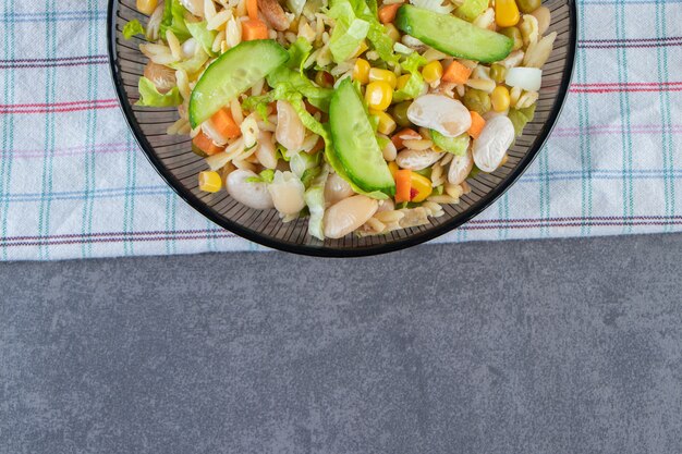 Zwei Schüsseln Gemüsesalat und geschnittene Karotten auf einem Geschirrtuch auf der Marmoroberfläche