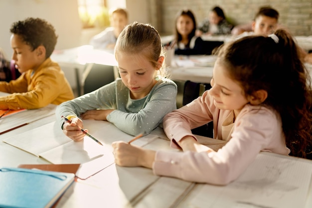 Zwei Schulmädchen, die gemeinsam an einer Aufgabe im Klassenzimmer arbeiten