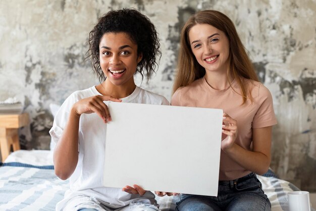 Zwei Smiley-Freunde, die leeres Plakat im Bett halten