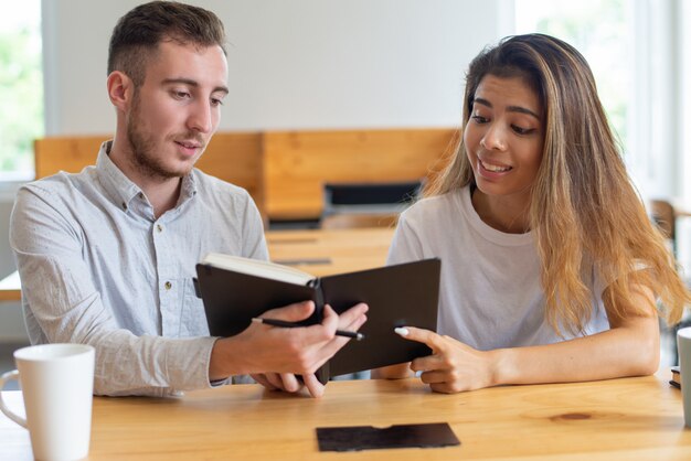 Zwei Studenten, die Lehrbuch lesen und zusammen studieren