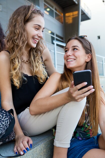 Zwei Studenten haben Spaß mit Smartphones nach dem Unterricht.