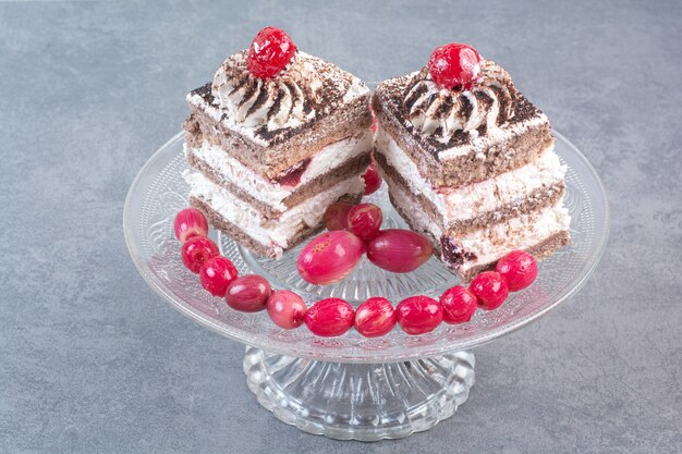 Zwei süße leckere Kuchen mit Hagebutten auf Glasplatte.