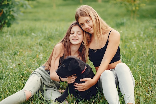 Zwei süße Mädchen in einem Sommerpark mit einem Hund