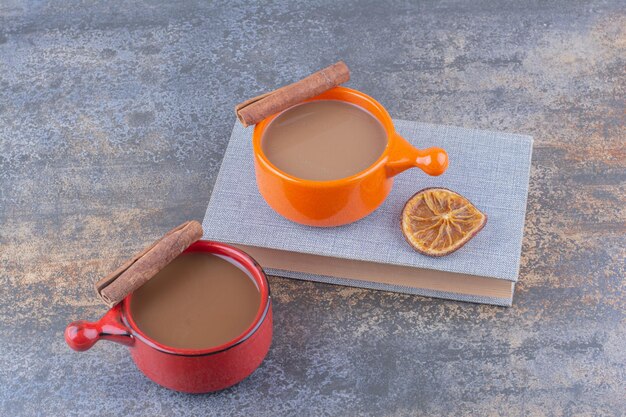 Zwei Tassen Kaffee, Buch und Zimtstangen. Foto in hoher Qualität