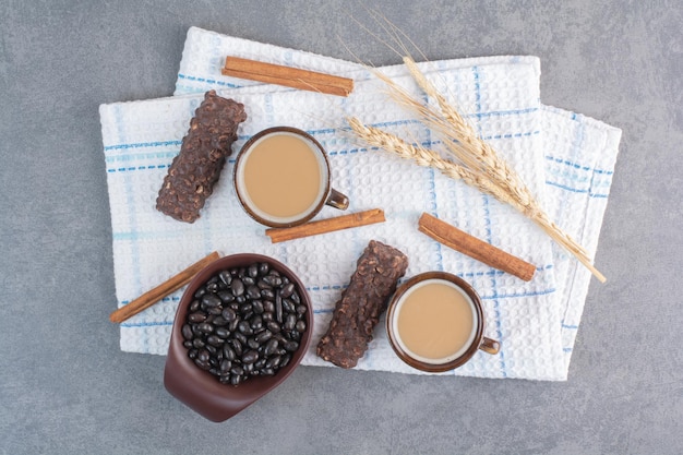 Zwei Tassen Kaffee mit Blatt Papier und Pralinen auf Tischdecke