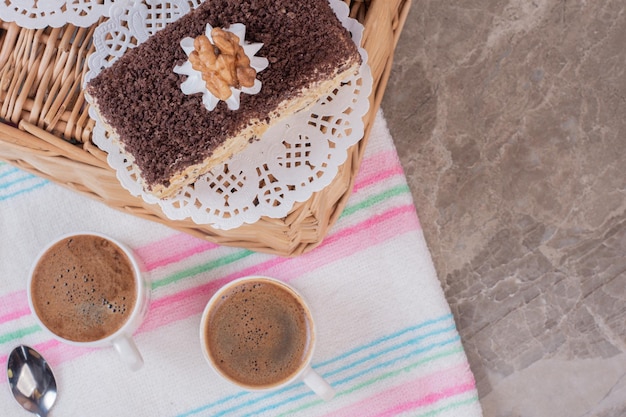 Zwei tassen kaffee mit süßem kuchen auf marmortisch