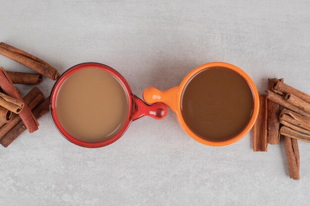 Zwei Tassen Kaffee und Zimtstangen auf Marmoroberfläche