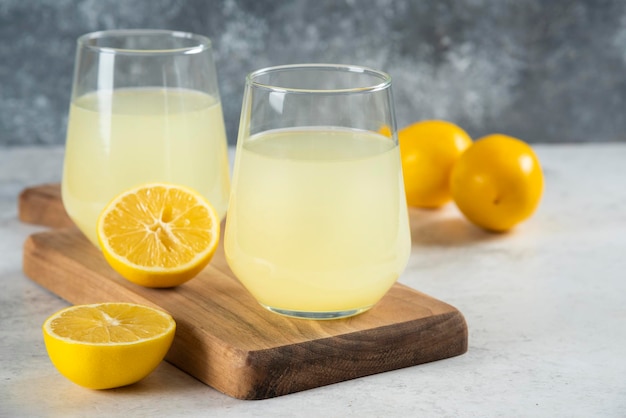 Zwei Tassen leckere Limonade auf einem Holzbrett.