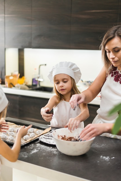 Zwei Töchter und Mutter, die Plätzchen in der Küche zubereiten