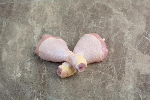 Zwei ungekochte Hühnerbeine auf Marmorhintergrund. Foto in hoher Qualität
