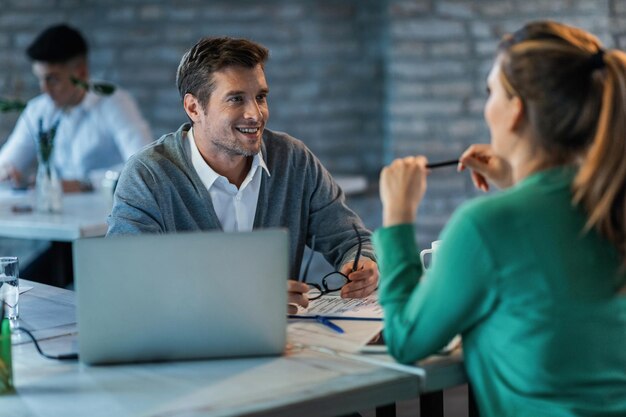 Zwei Unternehmer unterhalten sich während der Arbeit am Schreibtisch im Büro Der Fokus liegt auf einem glücklichen Geschäftsmann