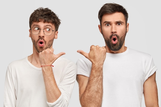 Zwei verblüffte Männer zeigen sich gegenseitig an und haben verblüffte Gesichtsausdrücke