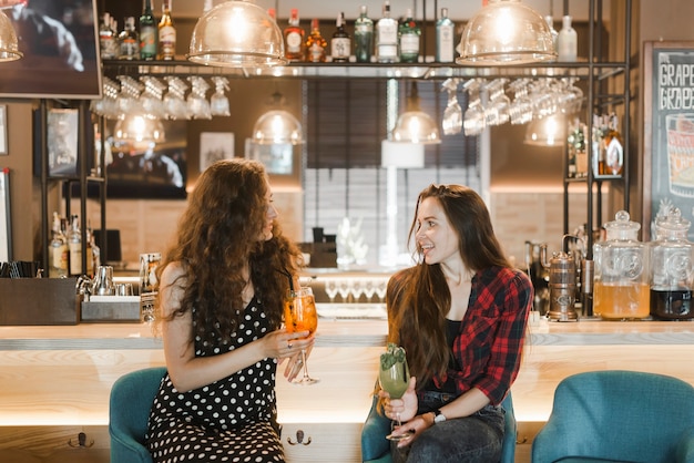 Zwei weibliche Freunde, die Getränke an der Bar genießen