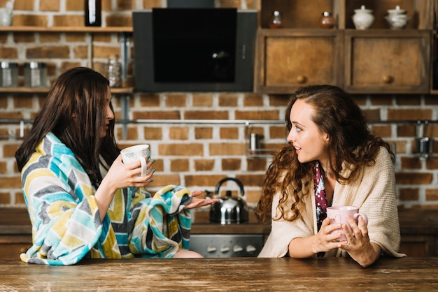 Zwei weibliche Freunde, die Tasse Kaffee in der Küche trinken