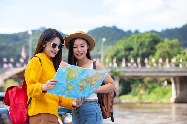 Zwei weibliche Touristen halten eine Karte, um Orte zu finden.