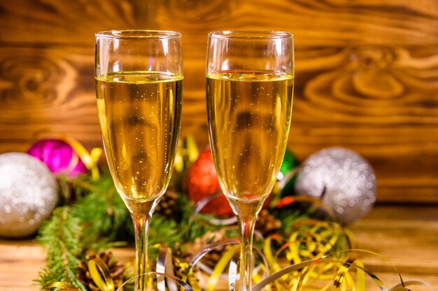 Zwei weingläser mit champagner und verschiedenen weihnachtsdekorationen auf rustikalem holztisch Premium Fotos