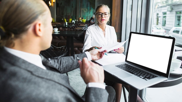 Zwei Wirtschaftler, die an Dokument mit Laptop auf Schreibtisch arbeiten