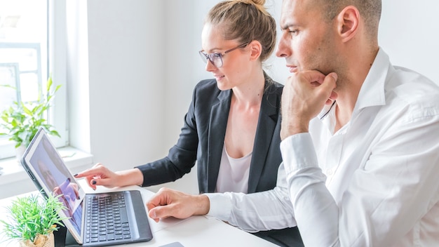 Zwei Wirtschaftler, die an Laptop am Arbeitsplatz arbeiten