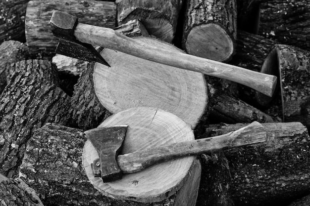 Zwei Äxte in Baumstümpfen Hintergrund gehacktes Brennholz Schwarz-Weiß-Foto