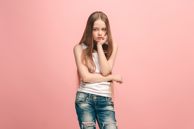 Zweifel Konzept. Zweifelhaftes, nachdenkliches trauriges jugendlich Mädchen, das sich an etwas erinnert. Menschliche Emotionen, Gesichtsausdruckkonzept. Teenager, der im Studio auf rosa Hintergrund aufwirft