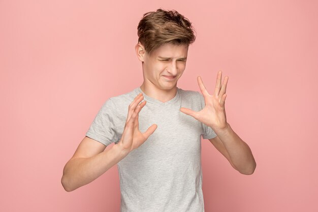 Zweifelhafter nachdenklicher Mann mit nachdenklichem Ausdruck, der Wahl gegen rosa Wand trifft