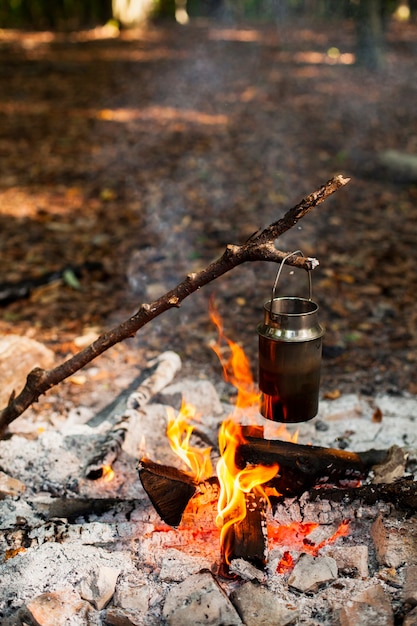 Zweig, der einen Behälter mit Wasser über dem Feuer hält