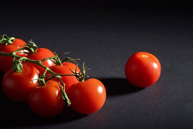 Zweig der roten Bio-Tomaten auf einem schwarzen