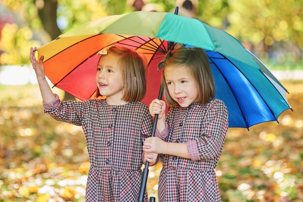 Zwillinge suchen Unterschlupf mit Regenschirm