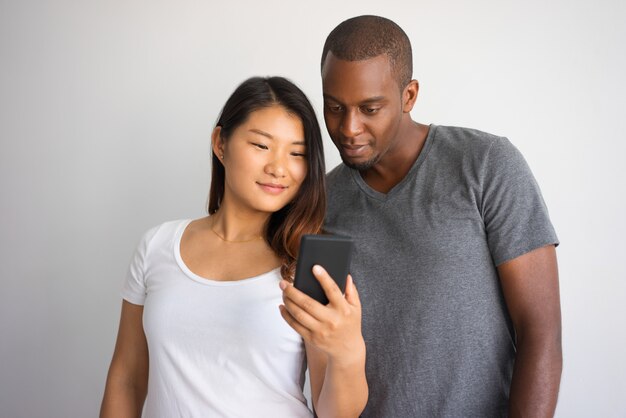 Zwischen verschiedenen Rassen Paare, die zusammen Smartphone verwenden.