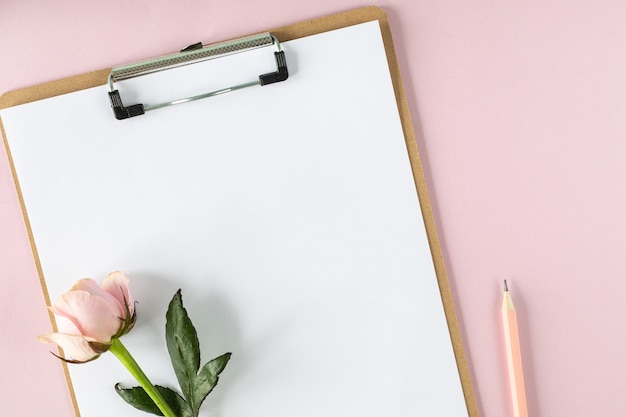 Zwischenablage Modell auf hellrosa Hintergrund mit rosa Rosen. Speicherplatz kopieren.