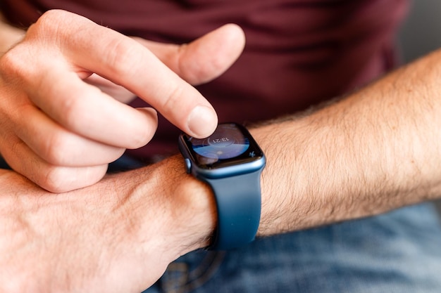 0232022 Moskau männliche Hand mit einem Handgelenk Smart Apple Watch junger Mann Menschen mit moderner Technologie durch Anpassen und Einstellen der Uhrzeit auf der Uhr durch Berühren des digitalen Bildschirms mit den Fingern