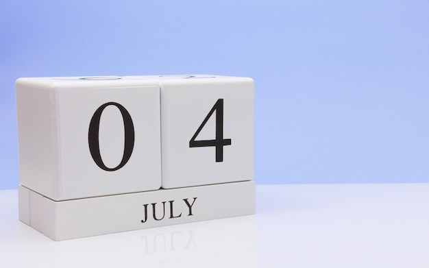 04 de julio. Día 4 del mes, calendario diario en mesa blanca con reflejo, con fondo azul claro.