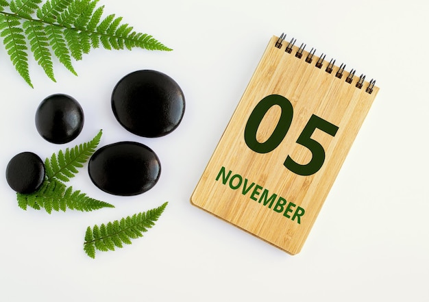 05 de noviembre 05 día del mes calendario fecha Bloc de notas negro SPA piedras hojas verdes Mes de otoño día del año concepto