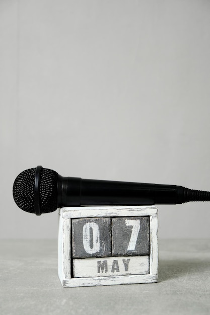 07 de maio, calendário de madeira e microfone preto, fundo cinzaConceito para o dia do rádio