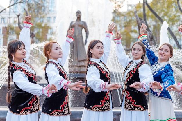 Foto 07 de mayo de 2021 ufa rusia el conjunto de canción y danza de bashkortostán en trajes nacionales posa contra el fondo de una fuente y una estatua de siete niñas bashkirs