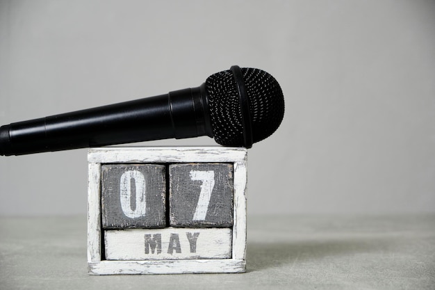 07 de mayo calendario de madera y micrófono negro fondo grisConcepto para el día de la radio