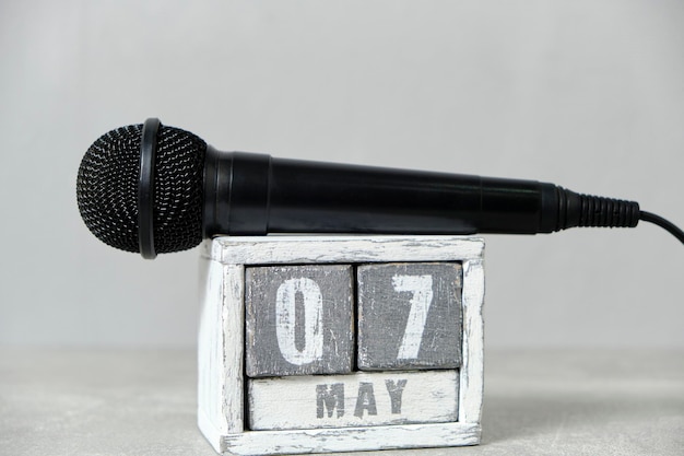 07 de mayo calendario de madera y micrófono negro fondo grisConcepto para el día de la radio