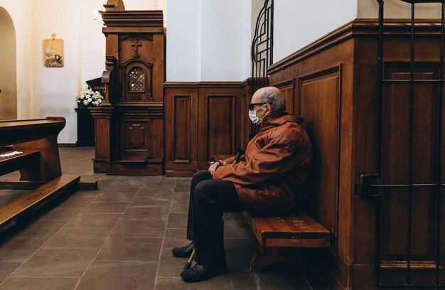 07062020 Vinnitsa Ucrânia um homem idoso com um bastão nas mãos e uma máscara no rosto senta-se no último banco da igreja durante a liturgia durante a pandemia de coronavírus