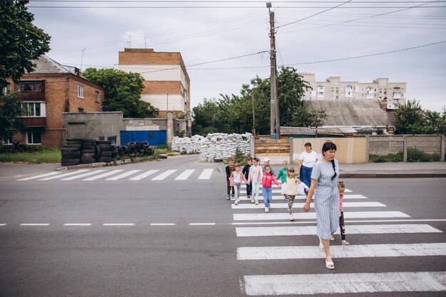 070722 Irpin Ucrânia crianças e seus professores andam em pares segurando uma caneta e se escondem em um bloqueio feito de sacos de areia durante um alerta de ataque aéreo