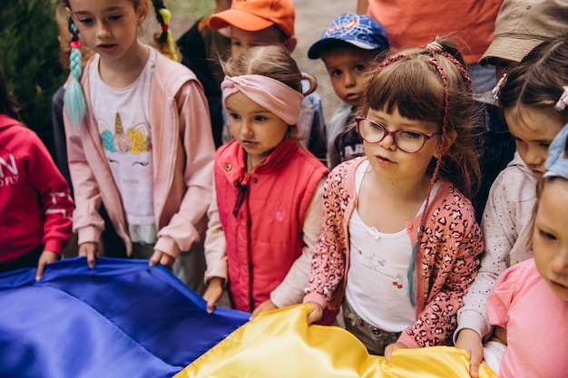 070722 Irpin Ukraine Christlicher Kindergarten Kinder mit der ukrainischen gelbblauen Flagge in der Hand beten für die Ukraine und den Frieden