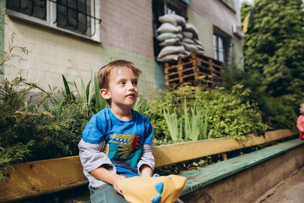 070722 Irpin Ukraine Kindergartenkinder spielen im Hof des Gebäudes, das mit einer Verkleidung und einem geschützten Sandsack versehen ist, um sich vor der Druckwelle zu schützen Wochentage der ukrainischen Kinder