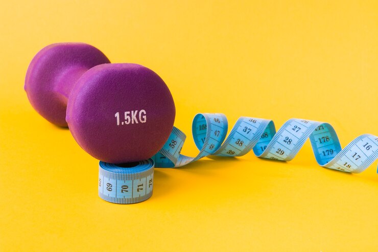 Foto 1,5 kilogramm lila hantel und blaues maßband auf gelber oberfläche