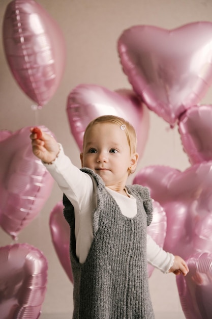 1. Geburtstagsbaby des netten kleinen Mädchens mit rosa Herzballonen und Geburtstagskuchen