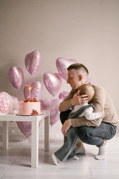 1. Geburtstagsbaby des netten kleinen Mädchens mit Vati und rosa Ballonherzballon-Fotozone