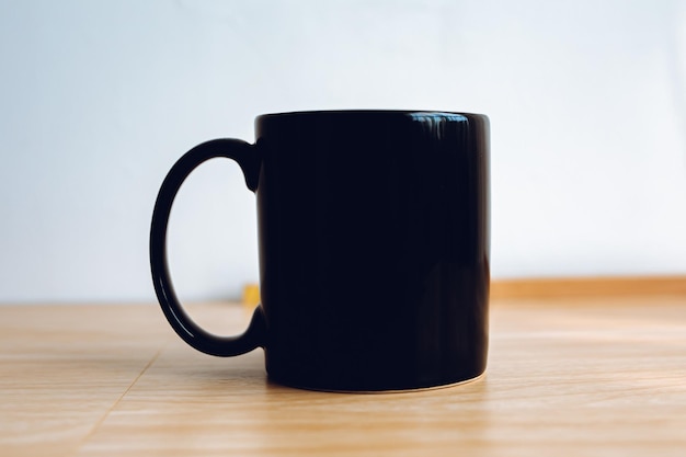 1 taza negra con suelo de madera y fondo blanco