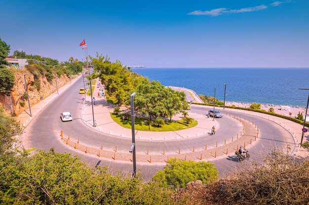 10 de julio de 2022 Antalya Turquía Coches y motocicletas suben por la sinuosa carretera serpenteante hasta la plataforma de observación con la bandera turca y una maravillosa vista del mar