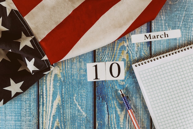 Foto 10 de marzo día calendario bandera de los estados unidos de américa símbolo de libertad y democracia con bloc de notas en blanco y bolígrafo sobre la mesa de madera