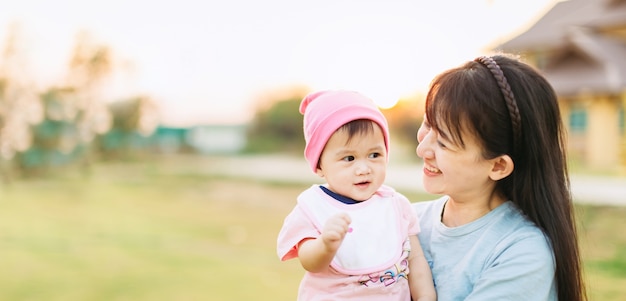 10 meses bebê fofo sentindo feliz e sorri com a mãe no jardim.